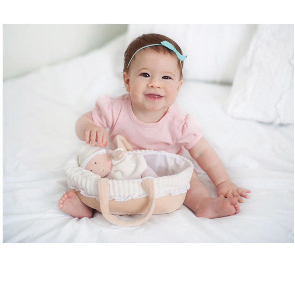 View of a young baby playing with a A personalised Bonikka rag doll baby in a cot with large carrying loops.  