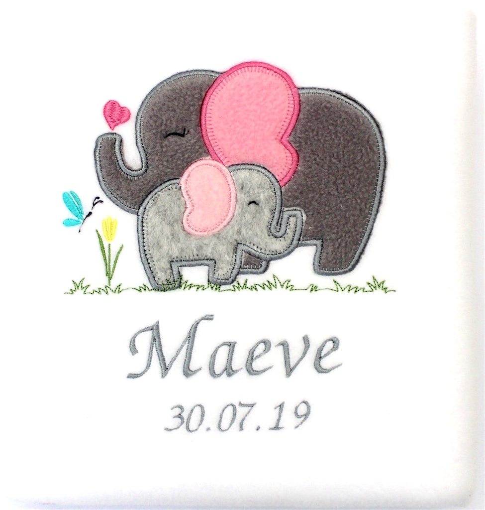 A folded beautiful white blanket embroidered with a mother elephant and her baby and personalised with name and date