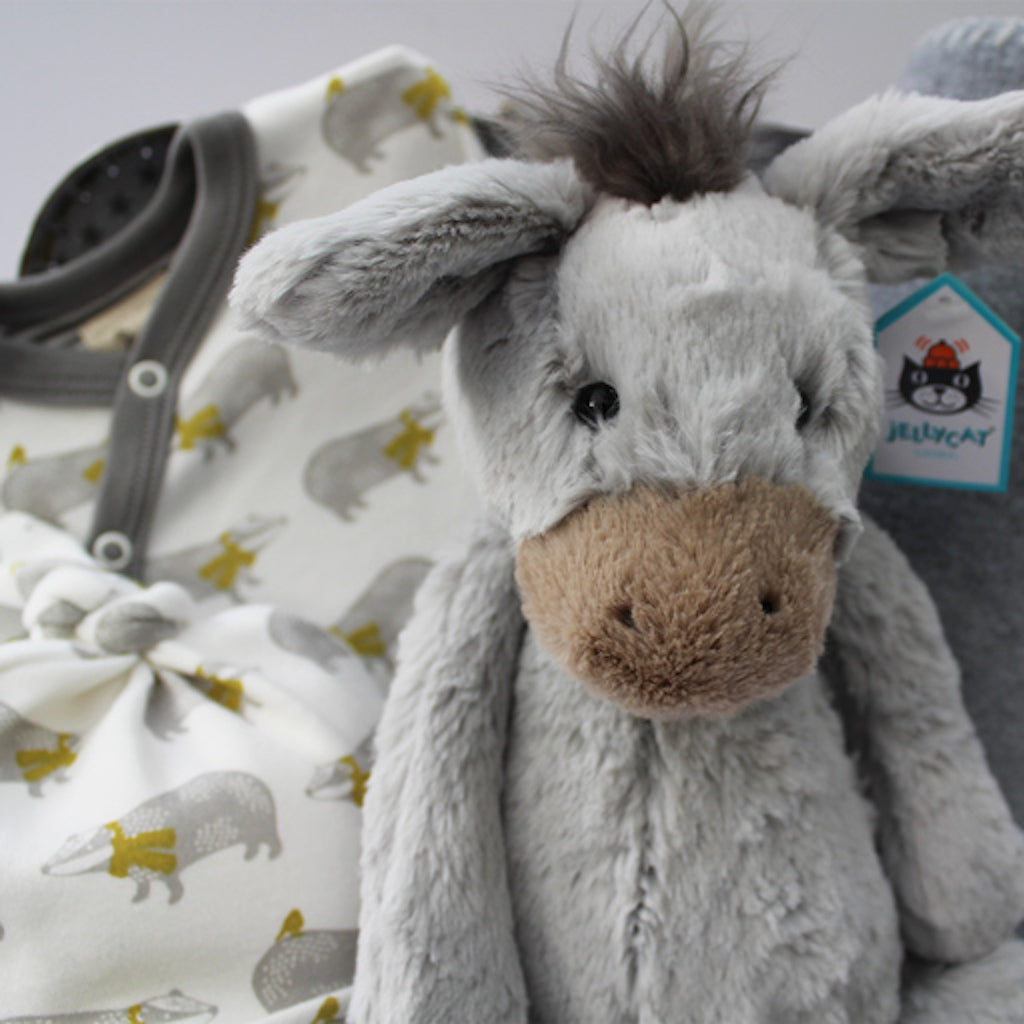 Jellycat Bashful Donkey grey soft toy in front of organic  badger sleepsuit by Pigeon