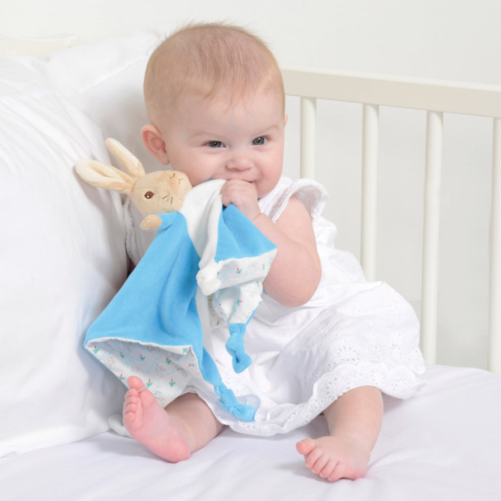 A beautiful baby holding a beautiful Peter Rabbit Comforter which has a soft blankie for cuddling and hugging